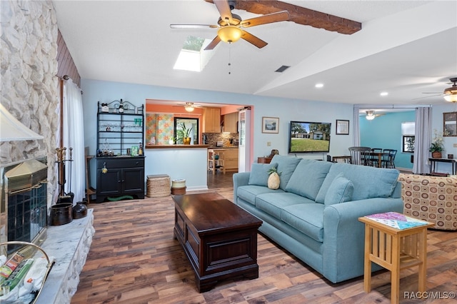 living room featuring lofted ceiling with skylight, a fireplace, ceiling fan, and dark hardwood / wood-style floors