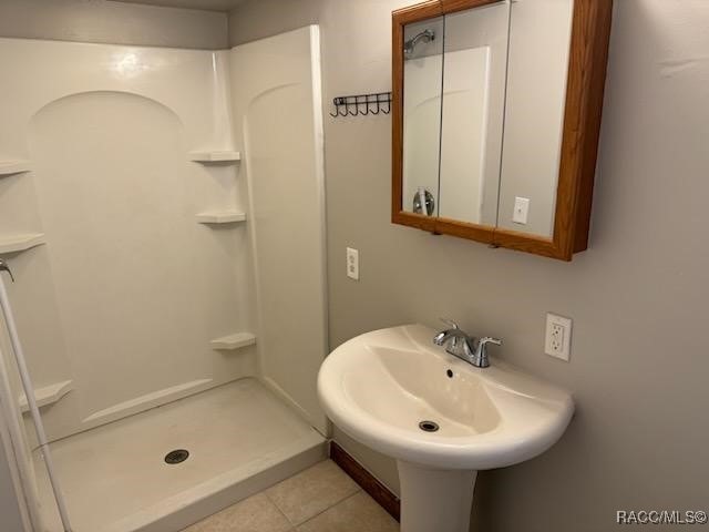 bathroom featuring tile patterned flooring, walk in shower, and sink