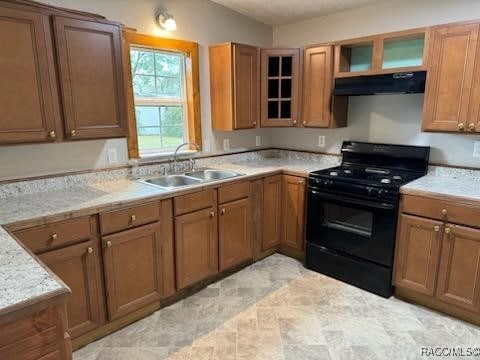 kitchen with light stone countertops, black gas range oven, and sink