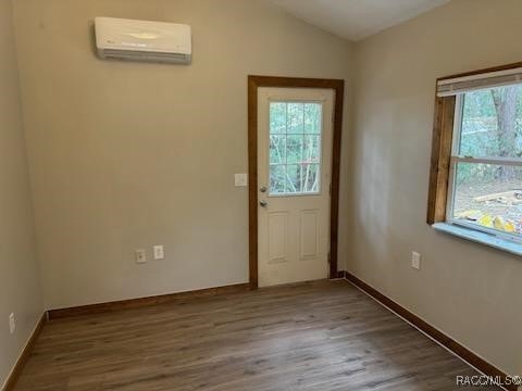 entryway with a wall unit AC, a healthy amount of sunlight, and wood-type flooring