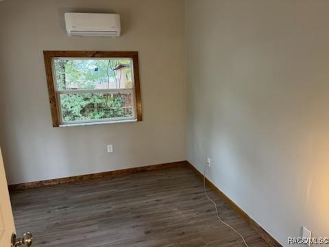 unfurnished room with an AC wall unit and dark wood-type flooring