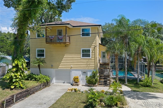 view of front of house featuring a lanai, a garage, a balcony, and a fenced in pool