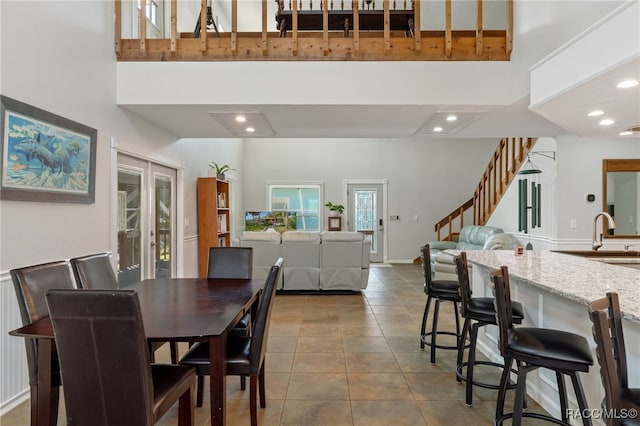 dining space with sink, a towering ceiling, french doors, and tile patterned flooring