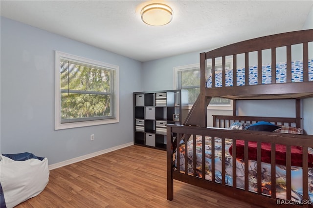 bedroom featuring hardwood / wood-style floors, a textured ceiling, and multiple windows