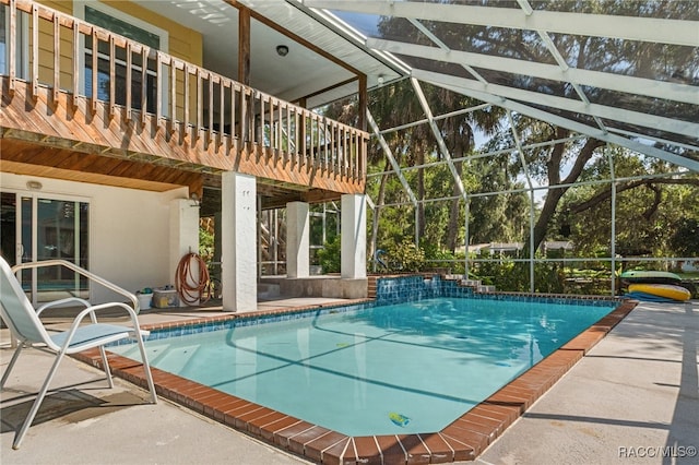 view of pool with glass enclosure, a patio area, and pool water feature