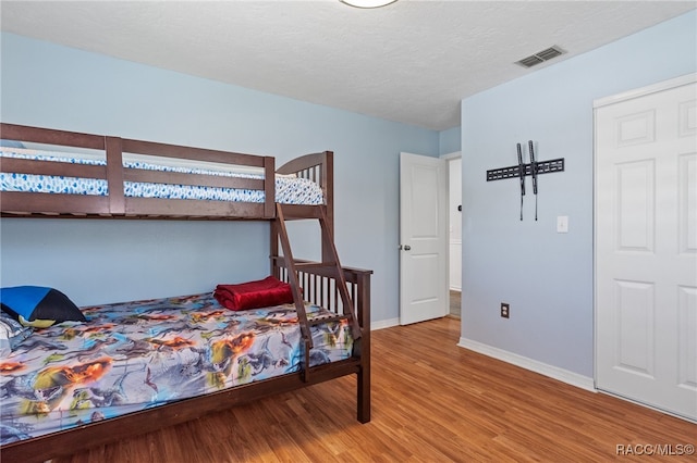 bedroom featuring hardwood / wood-style floors and a textured ceiling