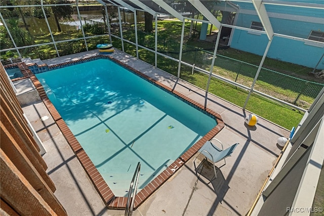 view of swimming pool with glass enclosure and a water view