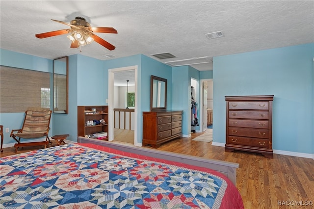 bedroom with hardwood / wood-style flooring, ceiling fan, a textured ceiling, and ensuite bath