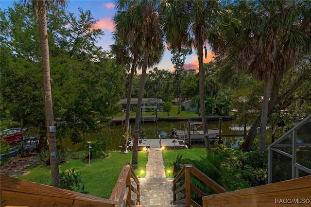 exterior space with a yard, a water view, and glass enclosure