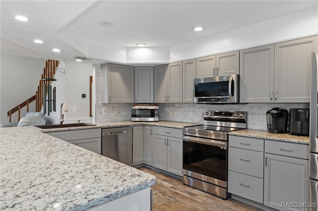 kitchen with appliances with stainless steel finishes, gray cabinetry, and hardwood / wood-style floors