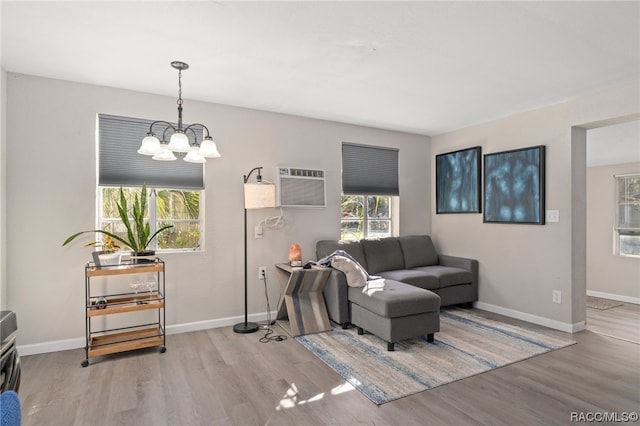 living room featuring light hardwood / wood-style floors, a wall mounted AC, a wealth of natural light, and a chandelier