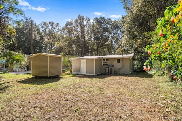 back of house with a lawn and a storage unit