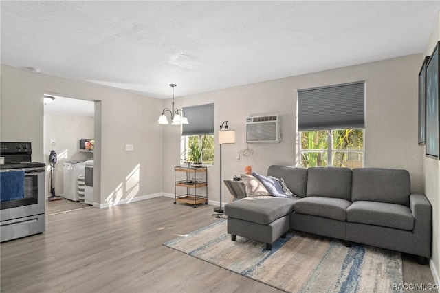 living room with a wall mounted air conditioner, hardwood / wood-style floors, washer / clothes dryer, and an inviting chandelier