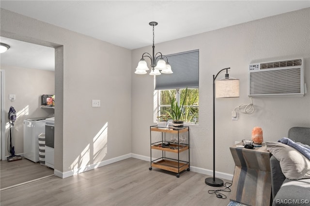 dining space featuring independent washer and dryer, an AC wall unit, light hardwood / wood-style flooring, and a notable chandelier