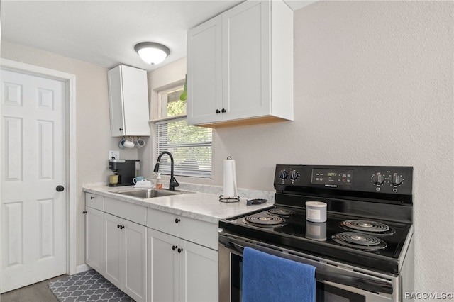 kitchen featuring white cabinets, light stone counters, electric stove, and sink