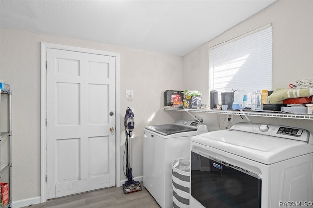 laundry area with independent washer and dryer and light hardwood / wood-style flooring