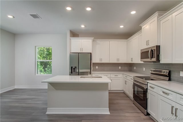 kitchen with decorative backsplash, wood finished floors, baseboards, a sink, and stainless steel appliances