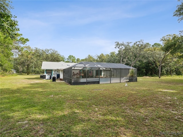 rear view of property with glass enclosure and a yard