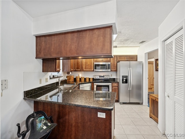 kitchen with dark stone countertops, sink, kitchen peninsula, and stainless steel appliances