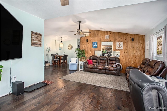 living room featuring ceiling fan, dark hardwood / wood-style floors, vaulted ceiling, and wood walls