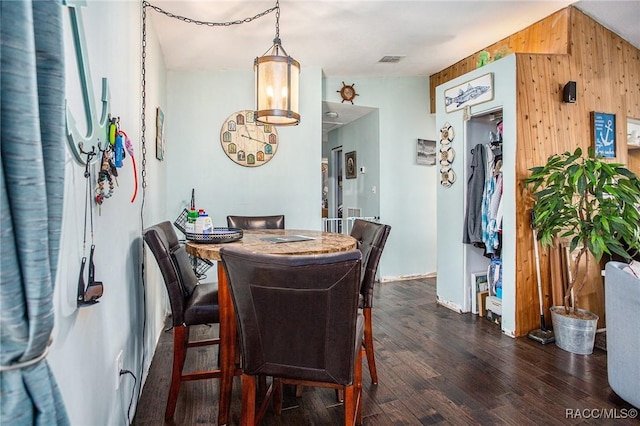 dining room with wooden walls and dark hardwood / wood-style flooring