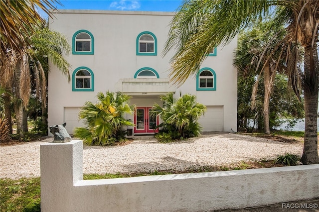 view of front of home with an attached garage, french doors, and stucco siding