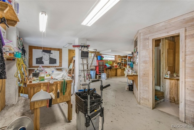 interior space with wooden walls, a workshop area, concrete floors, and visible vents