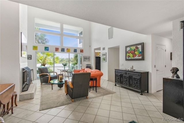 living room with light tile patterned flooring, a high ceiling, and a tiled fireplace