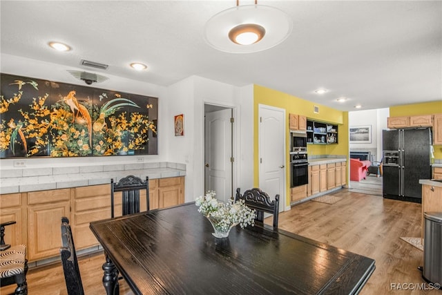 dining room with a fireplace, light wood-type flooring, and visible vents