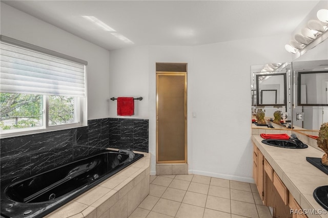 bathroom featuring tile patterned flooring, double vanity, baseboards, a tub with jets, and a shower stall