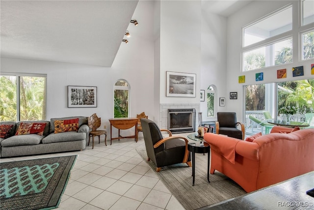 living room featuring light tile patterned floors, a wealth of natural light, a brick fireplace, and a towering ceiling