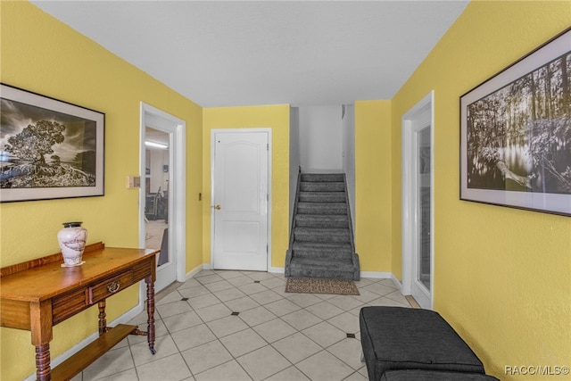 foyer entrance featuring baseboards, light tile patterned floors, and stairway