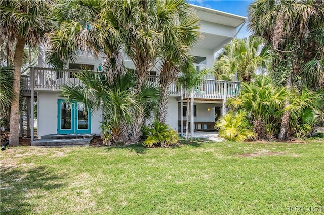 back of property featuring a lawn, a balcony, and stucco siding
