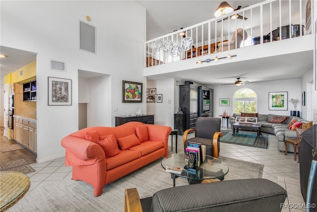 living area featuring ceiling fan, visible vents, light tile patterned floors, and a towering ceiling
