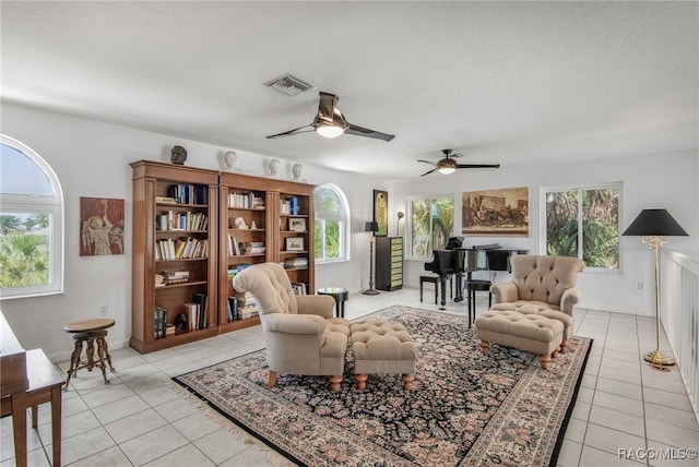 living area with ceiling fan, plenty of natural light, light tile patterned flooring, and visible vents