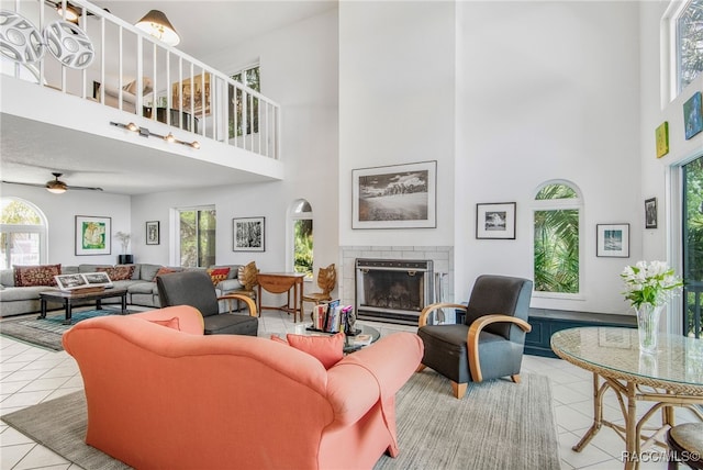living room featuring a wealth of natural light, tile patterned flooring, a fireplace, and a towering ceiling