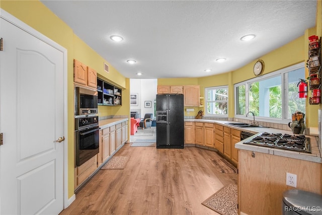 kitchen with visible vents, light brown cabinets, light wood-style floors, a sink, and black appliances