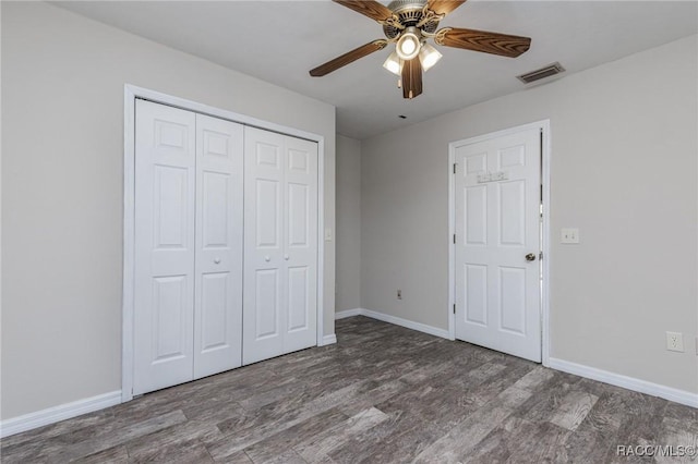 unfurnished bedroom with dark wood-style floors, a closet, visible vents, a ceiling fan, and baseboards