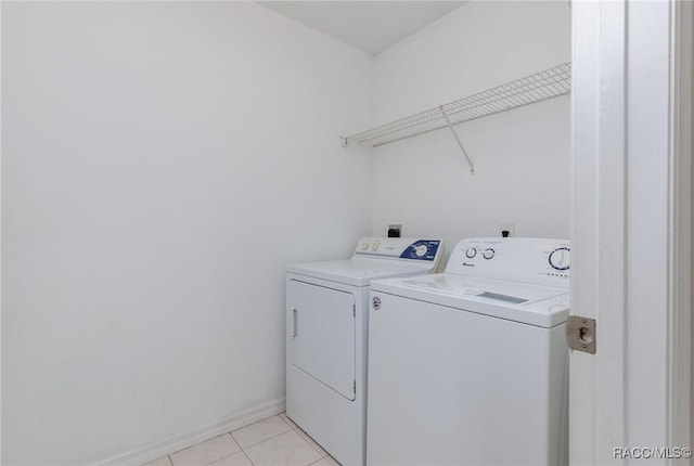 clothes washing area featuring laundry area, light tile patterned flooring, independent washer and dryer, and baseboards