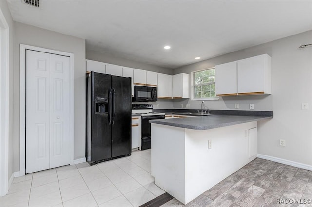 kitchen featuring dark countertops, white cabinetry, a sink, a peninsula, and black appliances