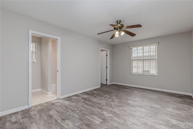 empty room with light wood-type flooring, a ceiling fan, and baseboards