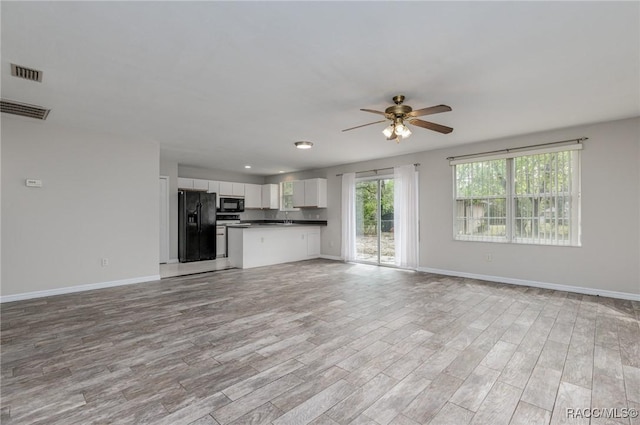 unfurnished living room with a ceiling fan, baseboards, visible vents, and light wood finished floors