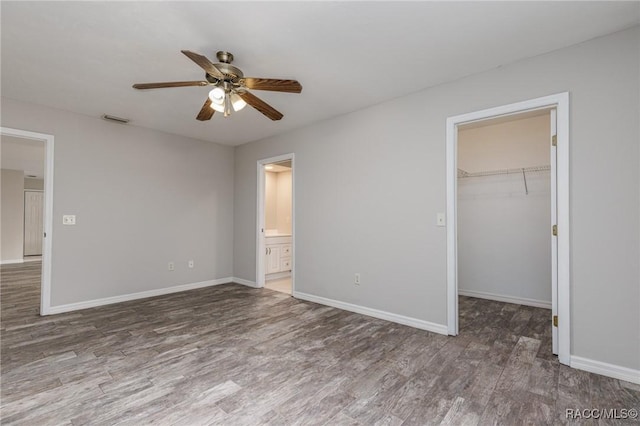 unfurnished bedroom with baseboards, visible vents, dark wood-style flooring, a spacious closet, and a closet