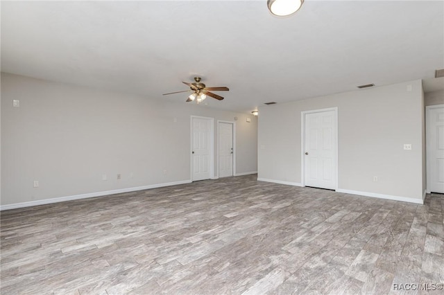 unfurnished room with light wood-style floors, visible vents, baseboards, and a ceiling fan