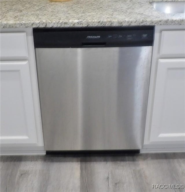 room details featuring white cabinetry, dark hardwood / wood-style flooring, dishwasher, and light stone countertops