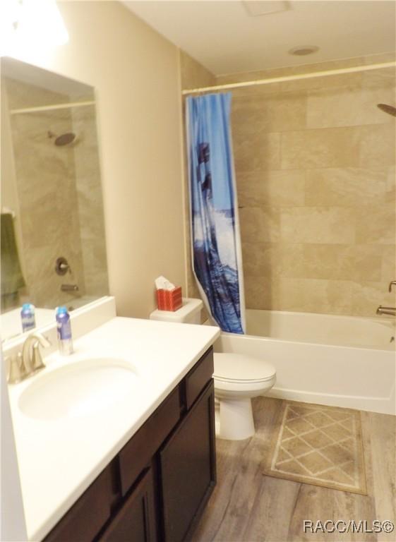 full bathroom with shower / tub combo with curtain, vanity, toilet, and hardwood / wood-style floors