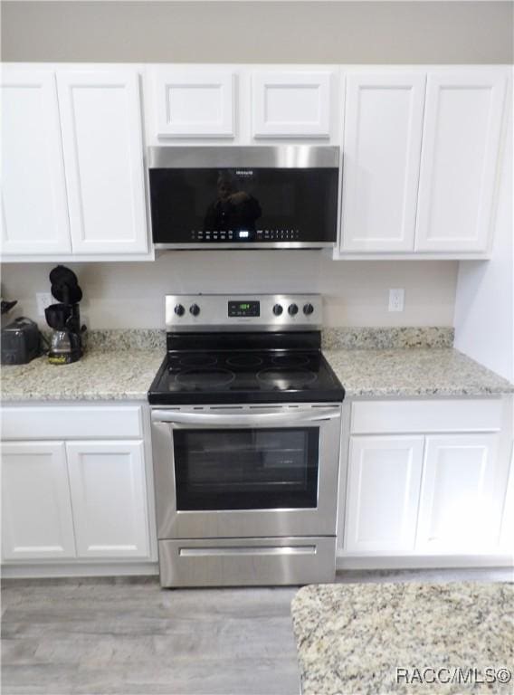 kitchen featuring light stone counters, stainless steel range with electric cooktop, and white cabinets