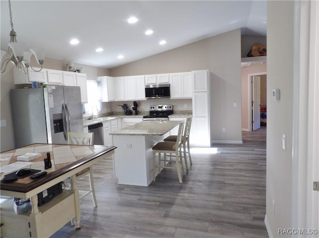 kitchen featuring a breakfast bar area, white cabinetry, decorative light fixtures, a center island, and stainless steel appliances