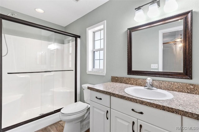 bathroom featuring a shower with door, vanity, hardwood / wood-style flooring, and toilet