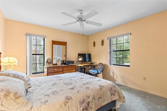 carpeted bedroom featuring ceiling fan, multiple windows, and a textured ceiling